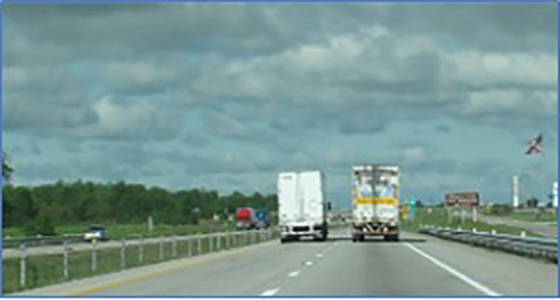 Image of highway, trailers, and sky.