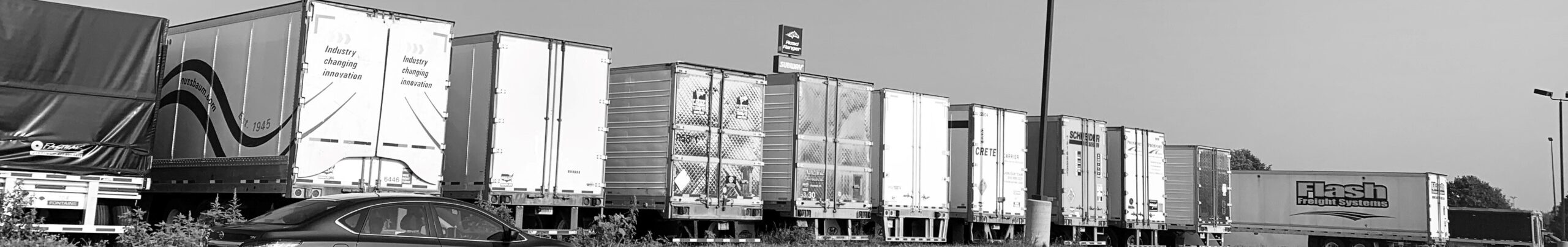 Ten tractor trailers parked in a row. View is from rear.